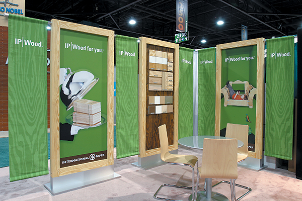 Graphics panels are flanked with hanging cloth banners unfurling the brand's green woodgrain design. Wood-framed panel equipped with peg system holds removable product samples.